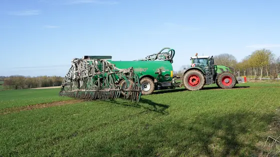 Broadcast spreader applying granular fertilizer across a healthy green North Alabama lawn